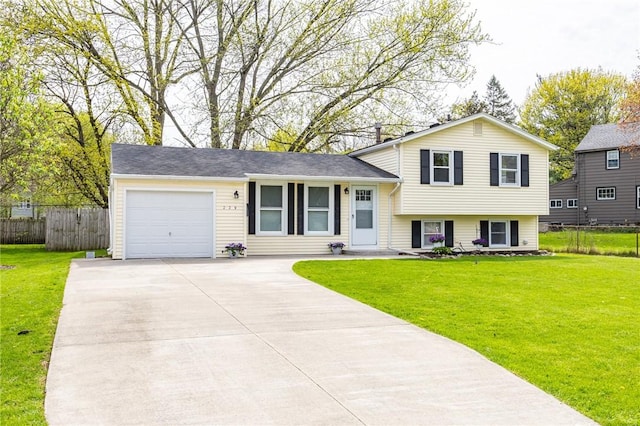 tri-level home featuring fence, driveway, a front lawn, and a garage