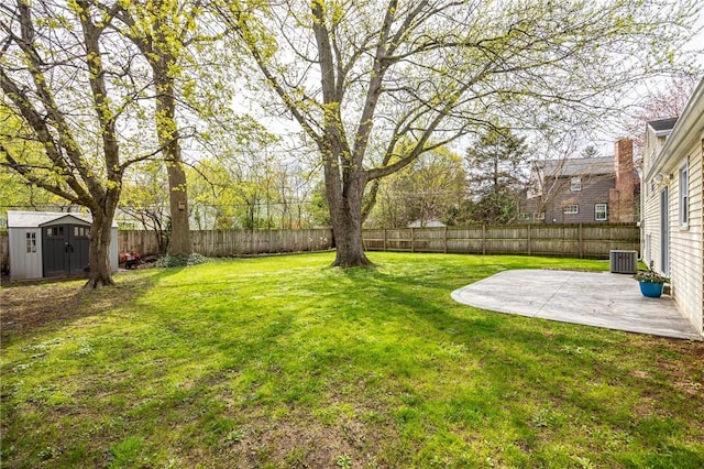 view of yard featuring a storage shed, a fenced backyard, an outbuilding, central AC unit, and a patio