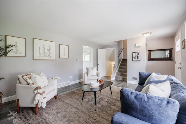 living area featuring stairway, baseboards, wood finished floors, and visible vents
