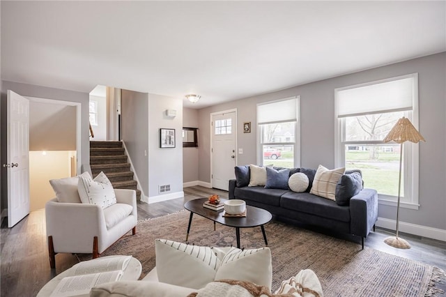 living area featuring stairs, baseboards, visible vents, and wood finished floors