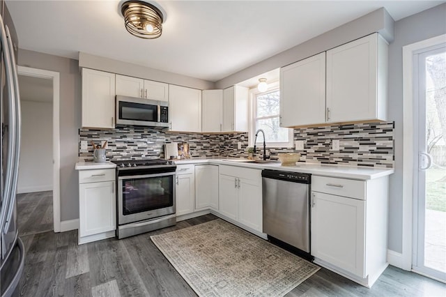 kitchen featuring a sink, appliances with stainless steel finishes, backsplash, and light countertops