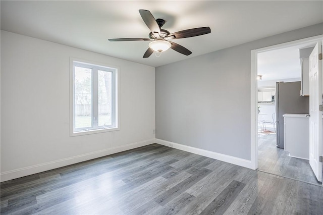 empty room with baseboards, a ceiling fan, and wood finished floors