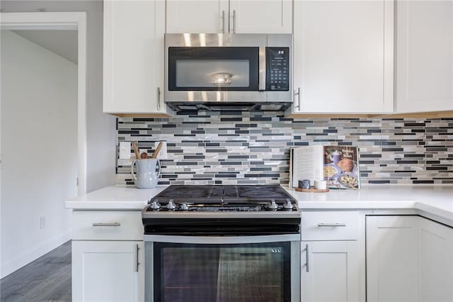 kitchen featuring baseboards, white cabinetry, wood finished floors, and stainless steel appliances