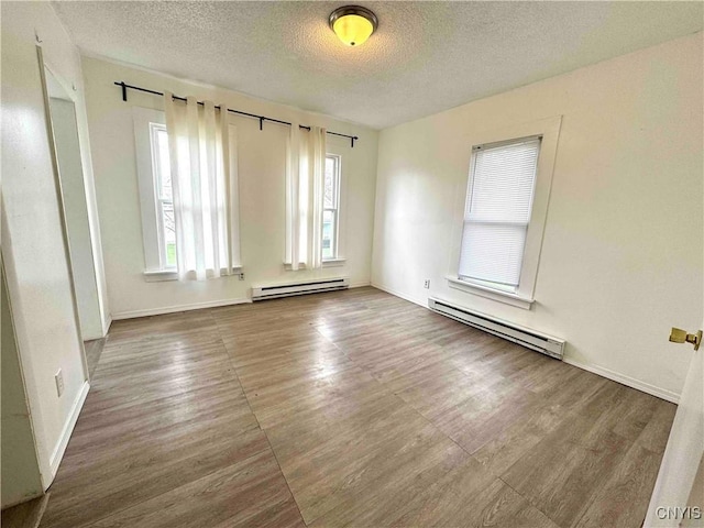 unfurnished room with baseboards, a baseboard radiator, a textured ceiling, and wood finished floors