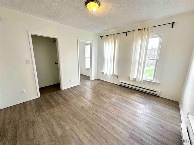 empty room with baseboards, a textured ceiling, a baseboard heating unit, and baseboard heating