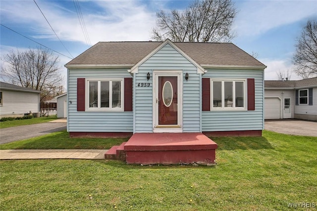 bungalow-style home with a shingled roof and a front yard