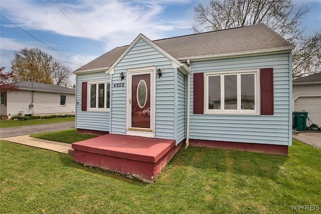 bungalow with a shingled roof and a front yard