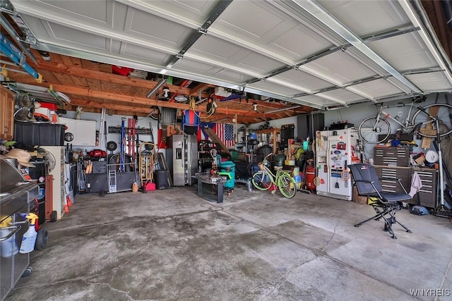 garage featuring white refrigerator with ice dispenser, a workshop area, and stainless steel fridge with ice dispenser