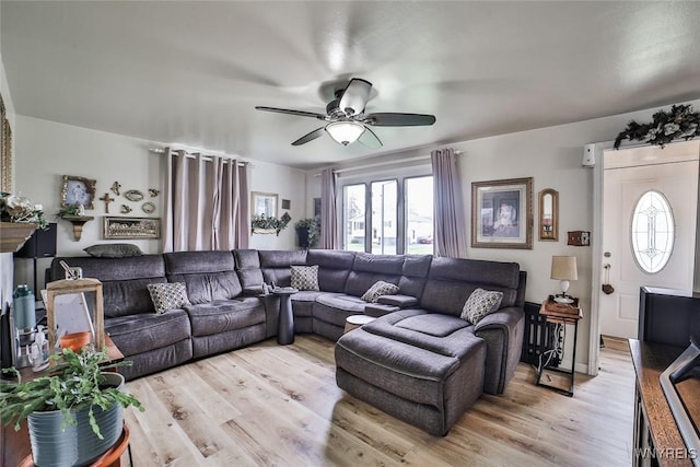 living area featuring a healthy amount of sunlight, ceiling fan, and light wood-style flooring