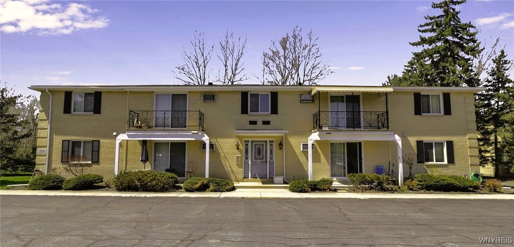 view of front of house with brick siding and a balcony