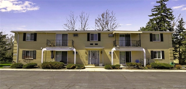 view of front of house with brick siding and a balcony