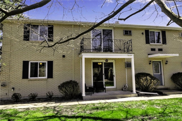 rear view of house featuring brick siding and a balcony