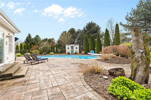 view of swimming pool with a patio area, fence, a fenced in pool, an outdoor structure, and a shed