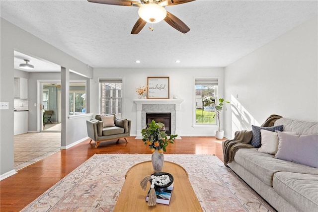 living area featuring a tiled fireplace, ceiling fan, recessed lighting, and wood finished floors