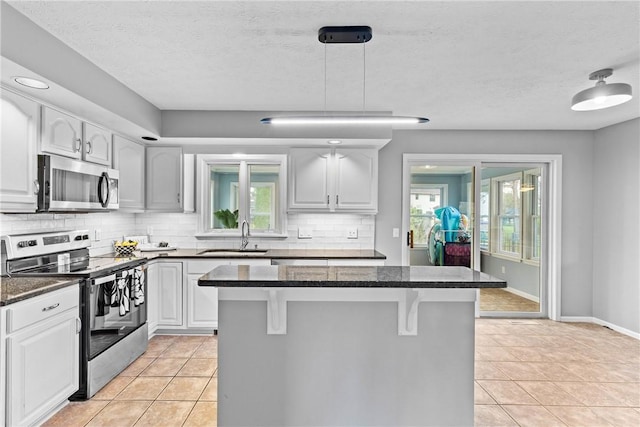kitchen featuring a sink, backsplash, light tile patterned floors, and stainless steel appliances