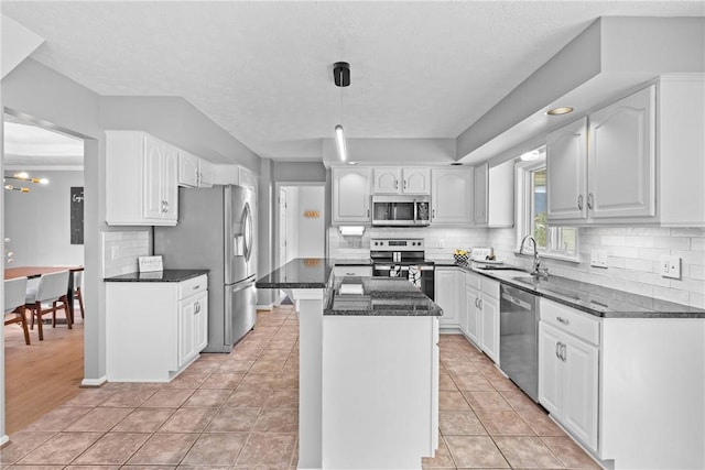 kitchen featuring white cabinets, appliances with stainless steel finishes, a sink, a center island, and backsplash