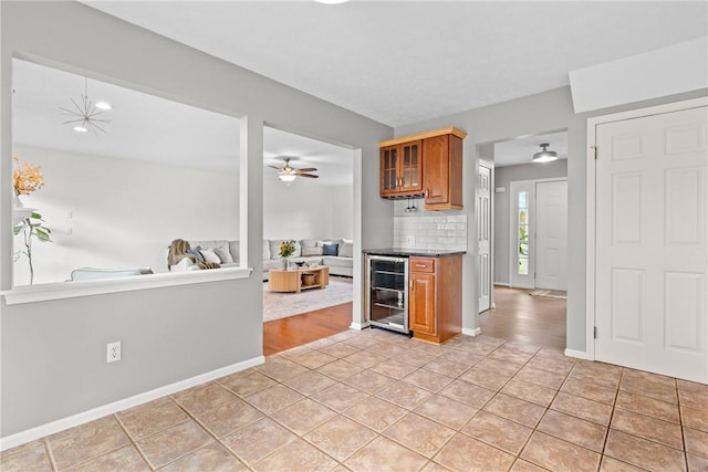 kitchen with light tile patterned flooring, glass insert cabinets, beverage cooler, open floor plan, and brown cabinets