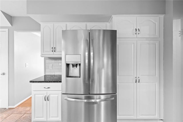 kitchen featuring dark stone counters, stainless steel refrigerator with ice dispenser, white cabinets, and decorative backsplash