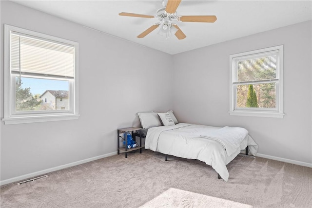 carpeted bedroom with baseboards, a ceiling fan, and visible vents
