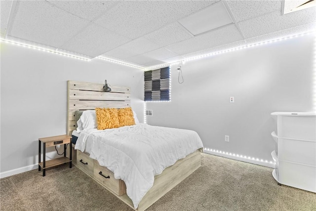 bedroom with baseboards, carpet flooring, and a drop ceiling