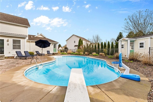 view of pool featuring fence, a fenced in pool, a patio area, a diving board, and an outbuilding