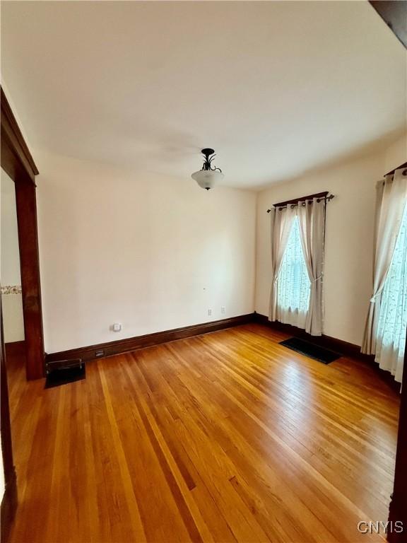 spare room with baseboards and light wood-style floors