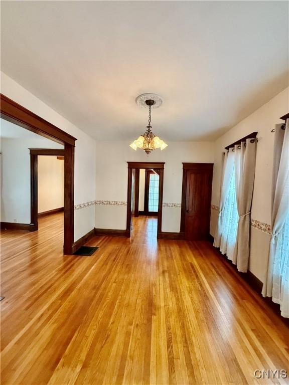 interior space with light wood-style floors, baseboards, and a chandelier