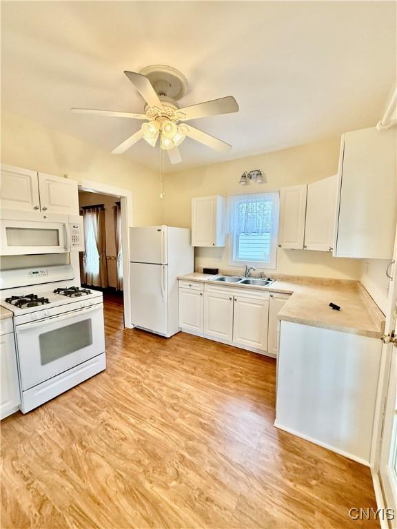 kitchen featuring white cabinets, a sink, white appliances, light countertops, and a ceiling fan