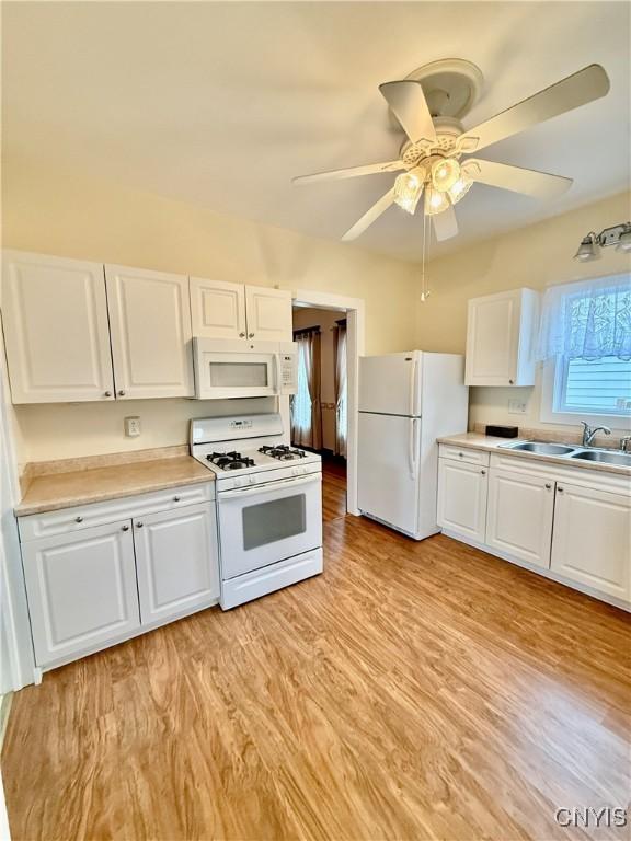 kitchen featuring light countertops, white cabinetry, light wood finished floors, and white appliances