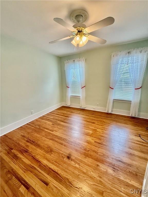 spare room featuring a ceiling fan, baseboards, and wood finished floors