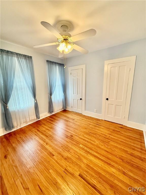 unfurnished bedroom featuring baseboards, ceiling fan, and light wood finished floors