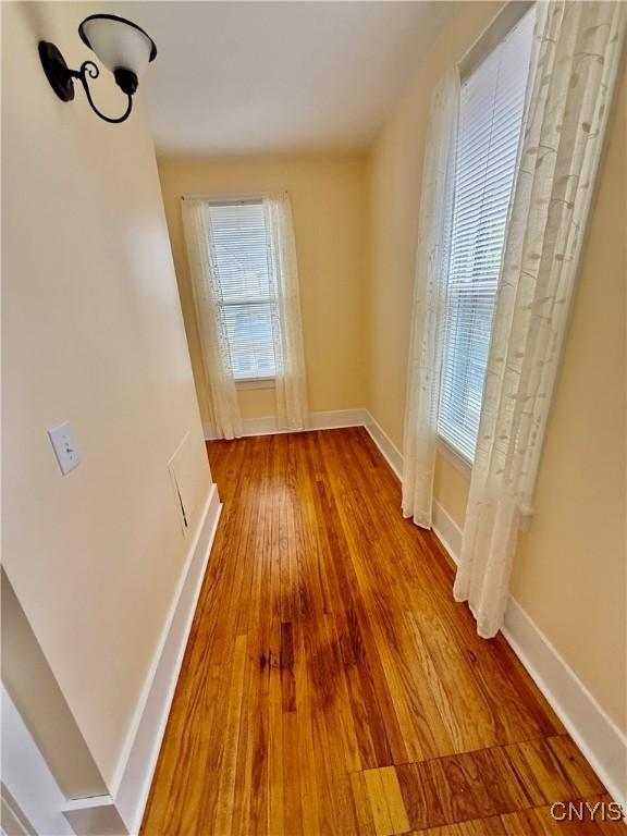 unfurnished dining area featuring baseboards, wood finished floors, and a wealth of natural light