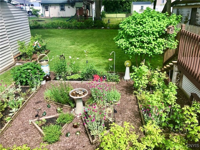 view of yard with fence, a playground, and a vegetable garden