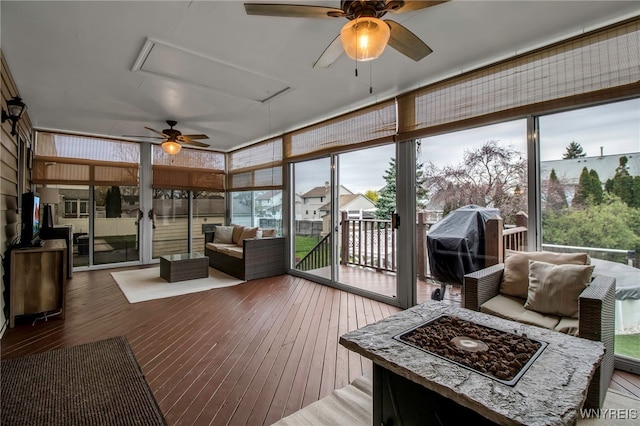 sunroom featuring a ceiling fan, a healthy amount of sunlight, and an outdoor living space with a fire pit