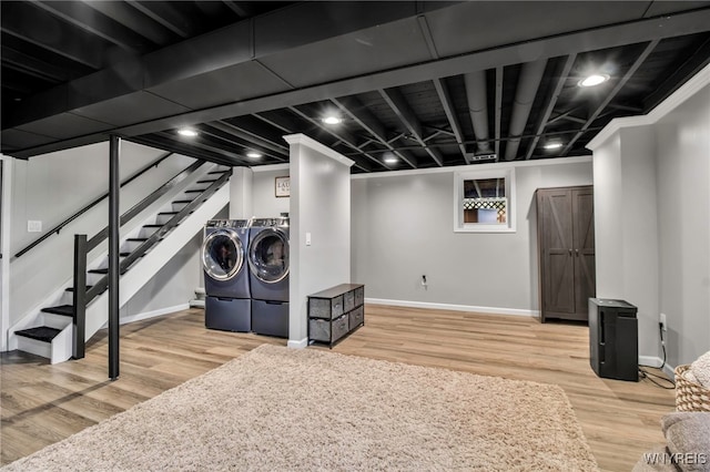 finished basement with baseboards, washer and clothes dryer, stairs, and wood finished floors