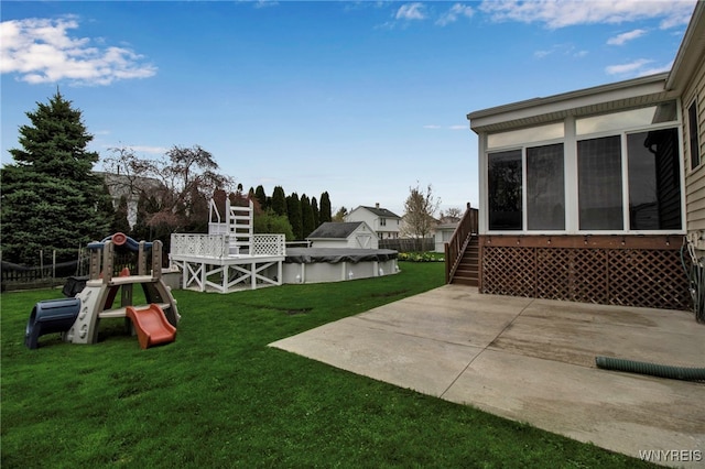 view of yard featuring a fenced in pool, a playground, a patio area, and a sunroom