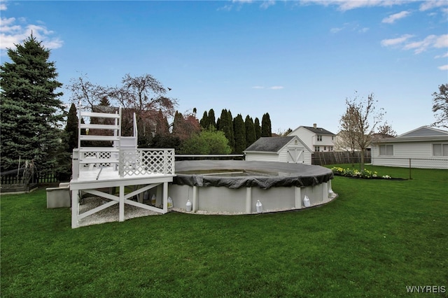 view of swimming pool featuring a lawn, fence, and a covered pool