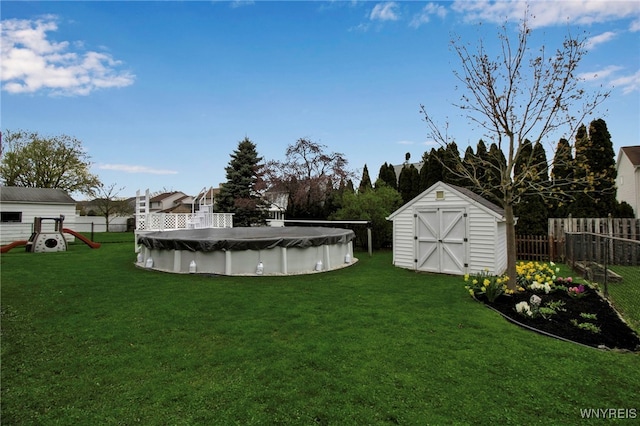 view of yard with a storage shed, an outbuilding, a fenced in pool, a fenced backyard, and a playground