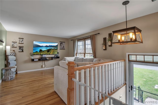 living room featuring baseboards, wood finished floors, and a notable chandelier