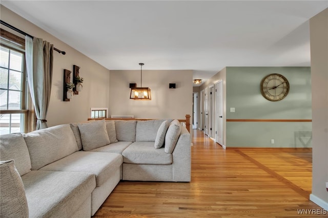 living room with light wood-style floors, baseboards, a notable chandelier, and a healthy amount of sunlight