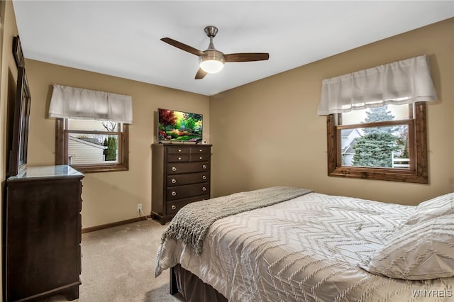bedroom with baseboards, ceiling fan, light carpet, and multiple windows