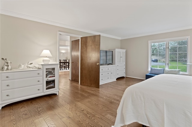 bedroom with crown molding, baseboards, and wood finished floors