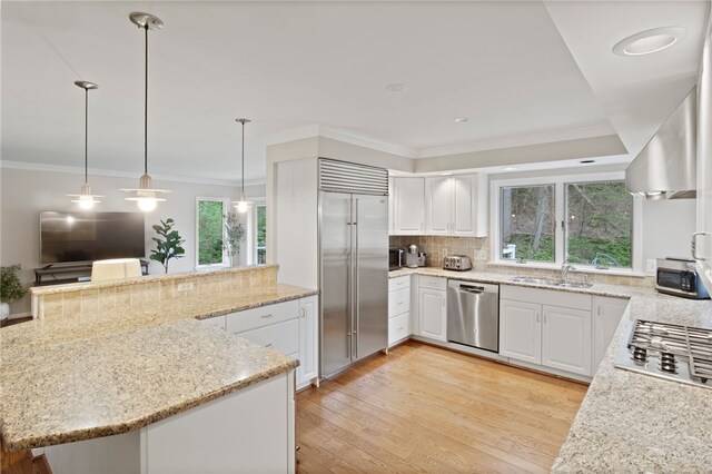 kitchen featuring decorative backsplash, ornamental molding, light stone counters, a sink, and appliances with stainless steel finishes