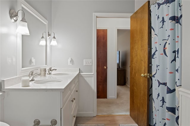full bath featuring a shower with shower curtain, double vanity, a sink, and wood finished floors