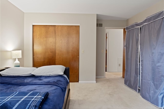 bedroom with a closet, baseboards, light colored carpet, and visible vents