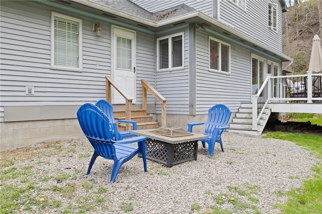 view of patio with entry steps, a fire pit, and a deck
