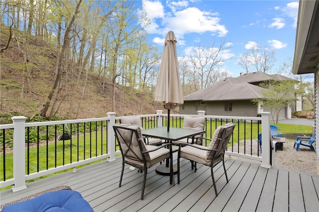 deck with outdoor dining area, a garage, and a lawn