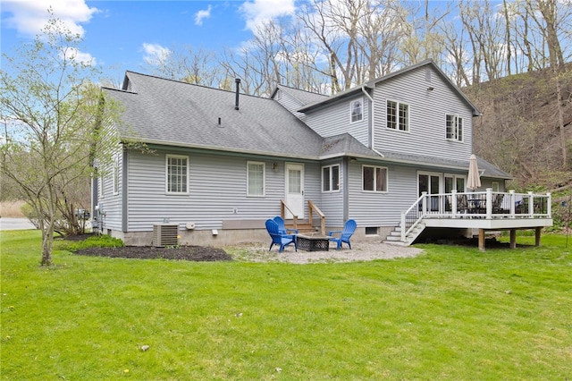 back of house featuring a lawn, a wooden deck, and a fire pit