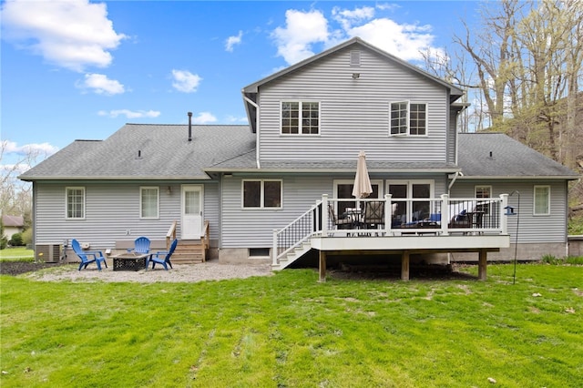 back of house featuring a lawn, a fire pit, and a wooden deck