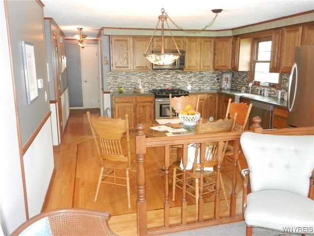 kitchen with brown cabinetry, tasteful backsplash, a sink, stainless steel appliances, and light wood-style flooring